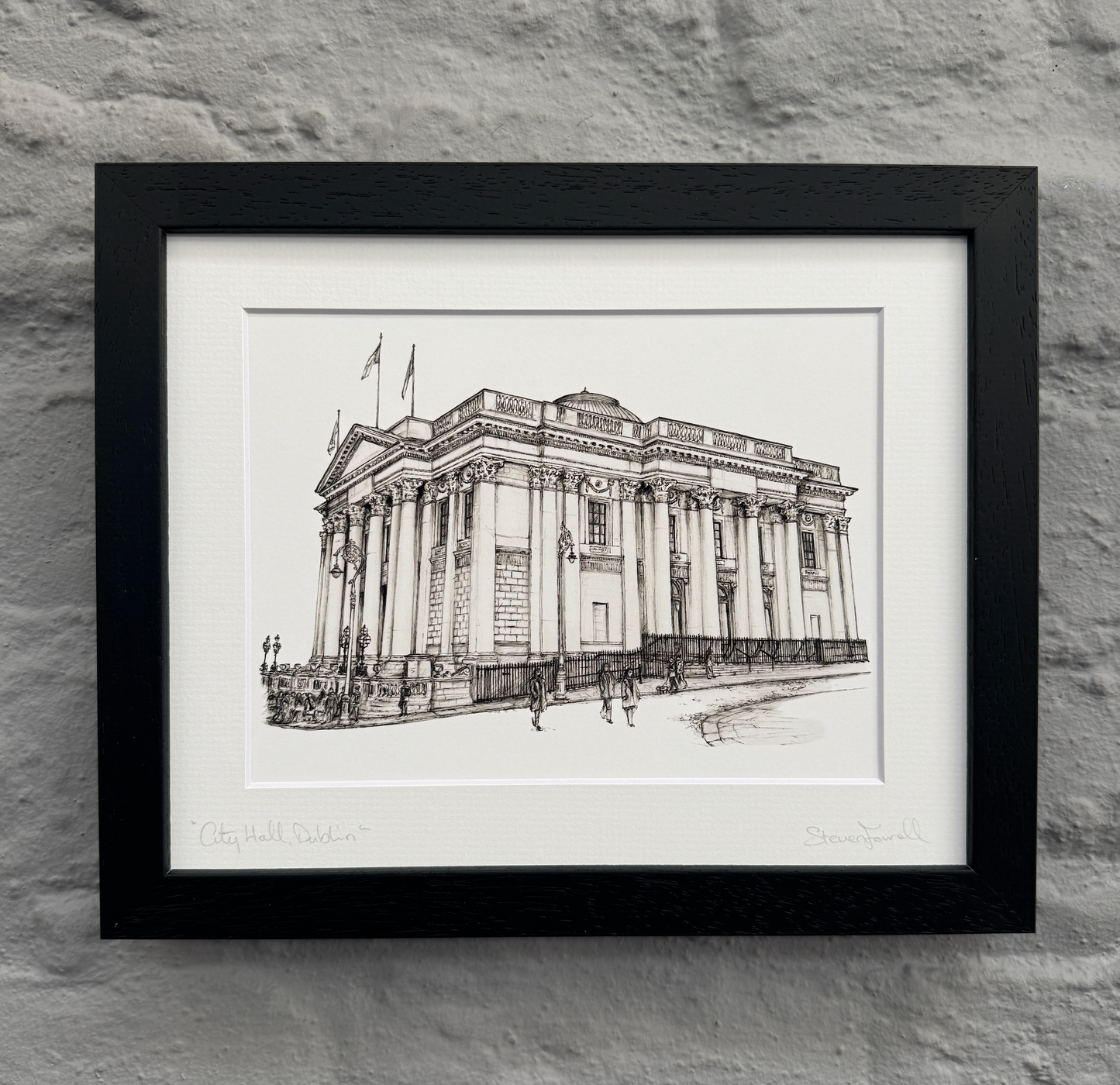 Framed black and white architectural drawing of a building on a stone wall background