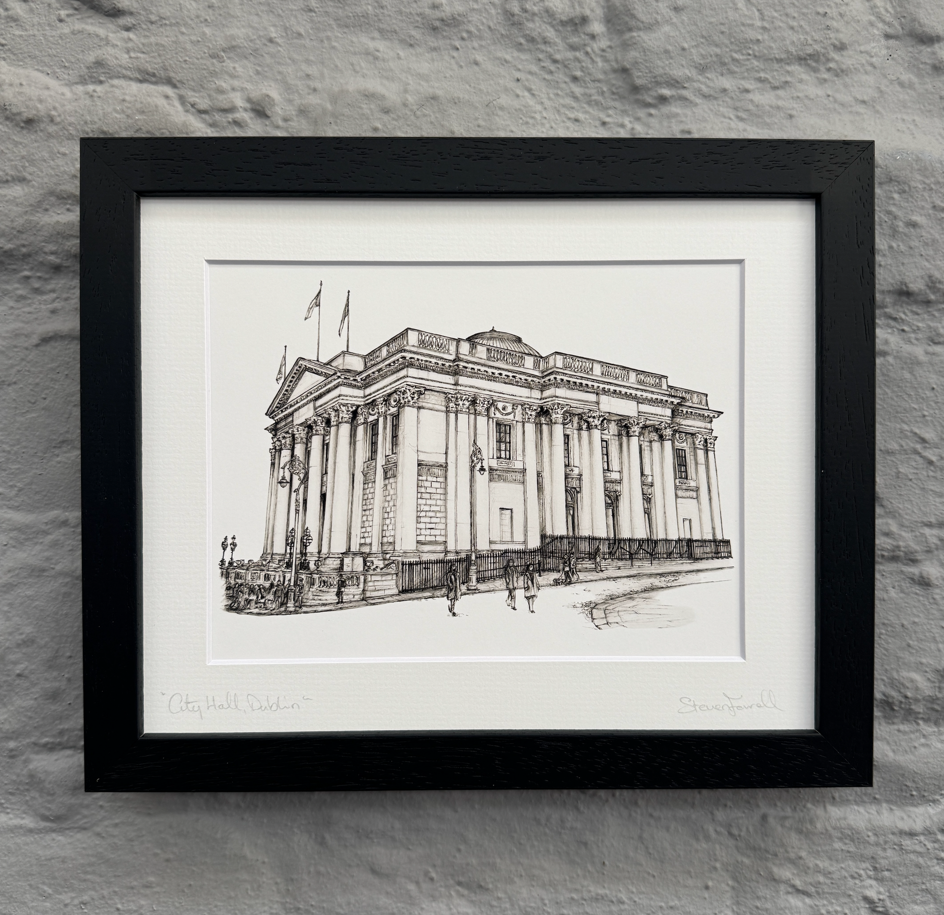 Framed black and white architectural drawing of a building on a stone wall background
