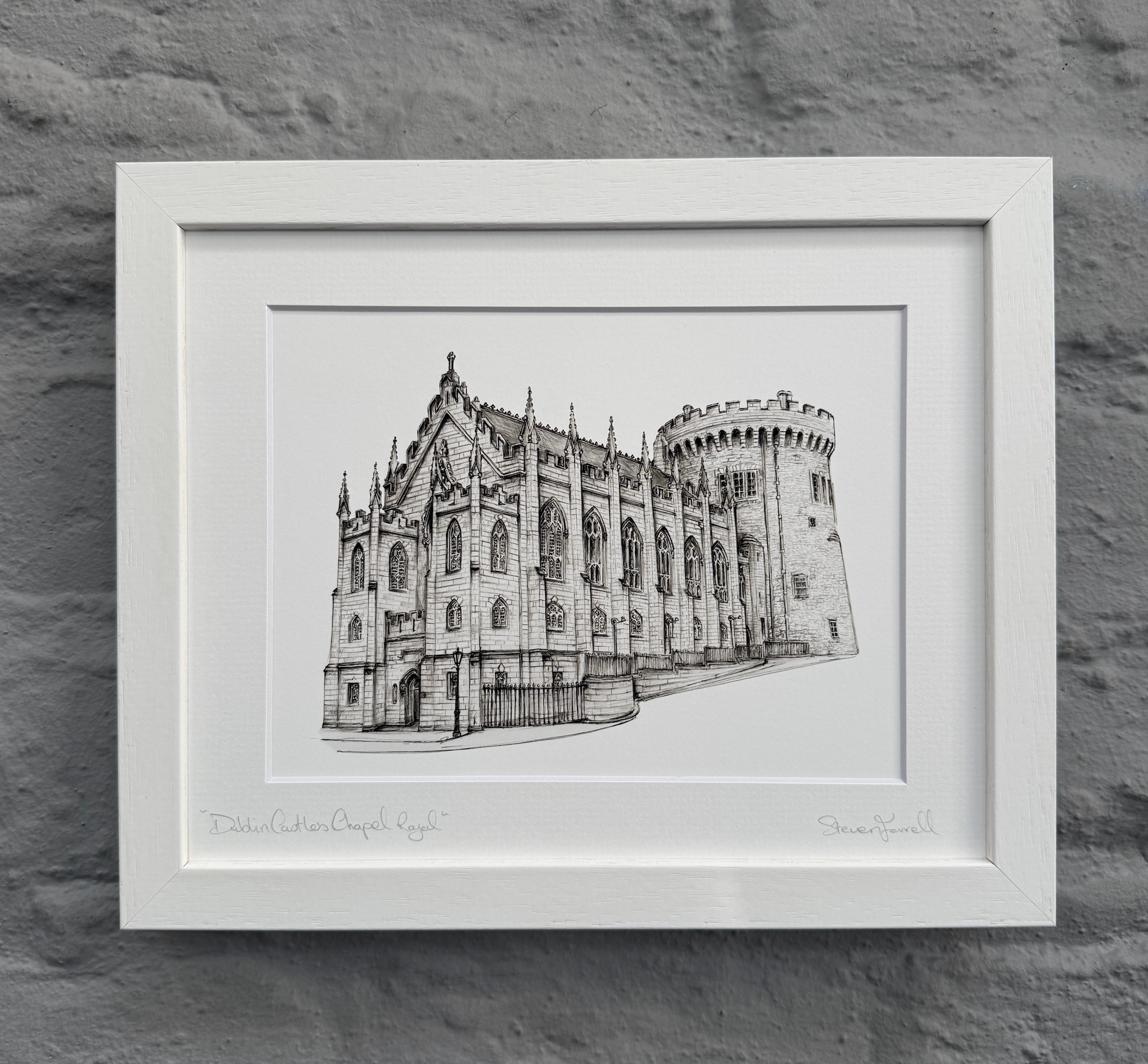 Framed black and white drawing of a castle on a stone wall