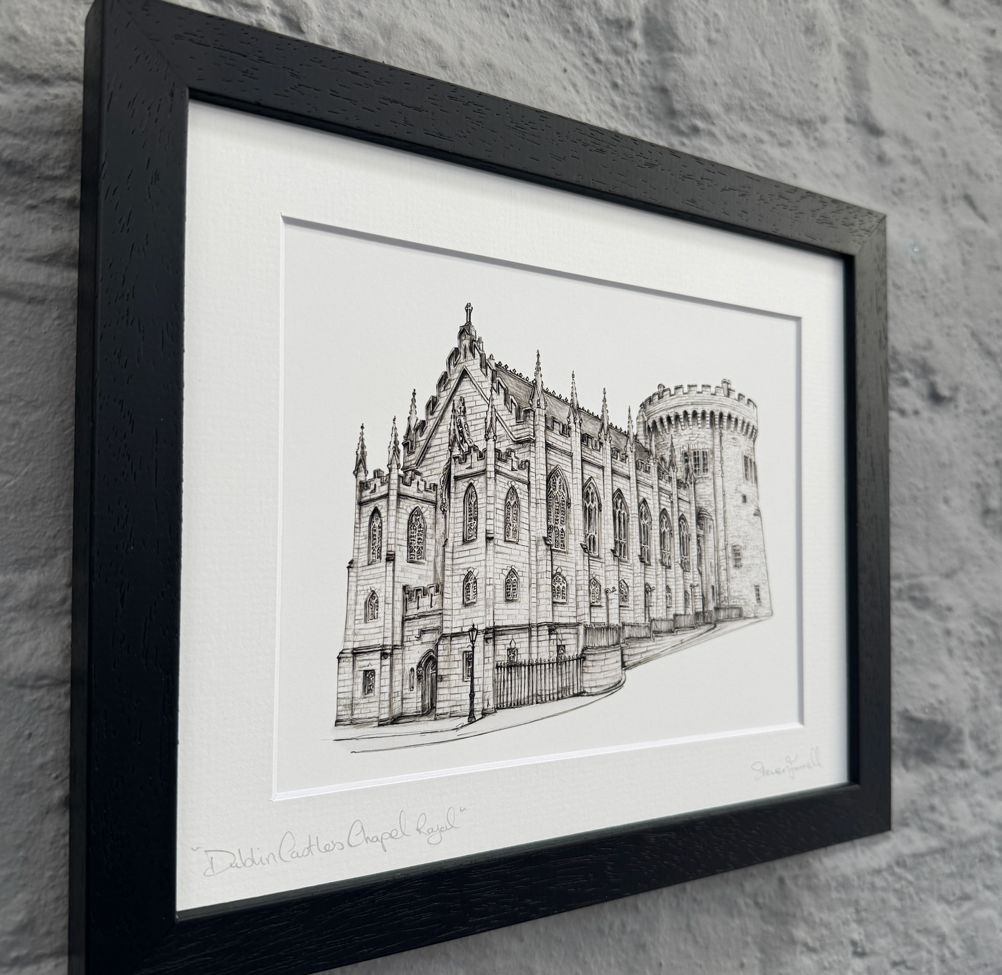Framed black and white architectural drawing of a building on a stone wall background