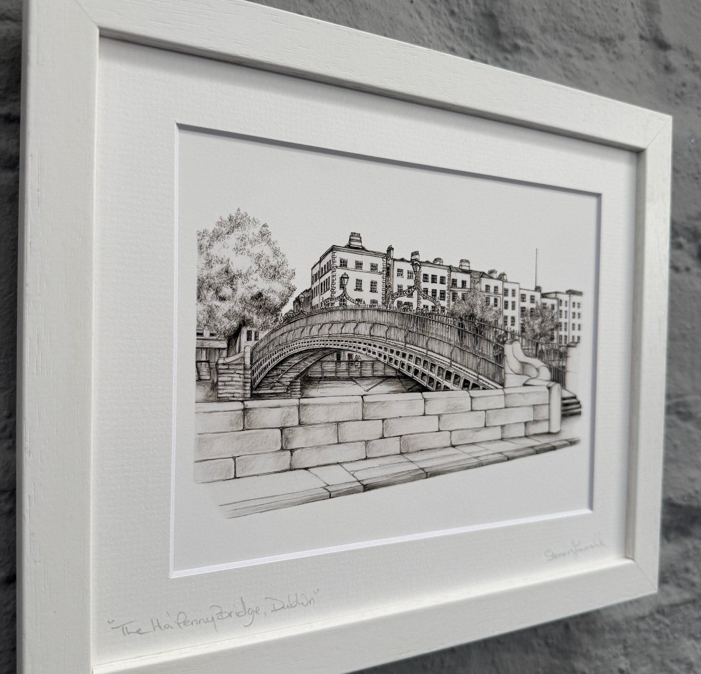 Framed black and white drawing of a bridge and buildings